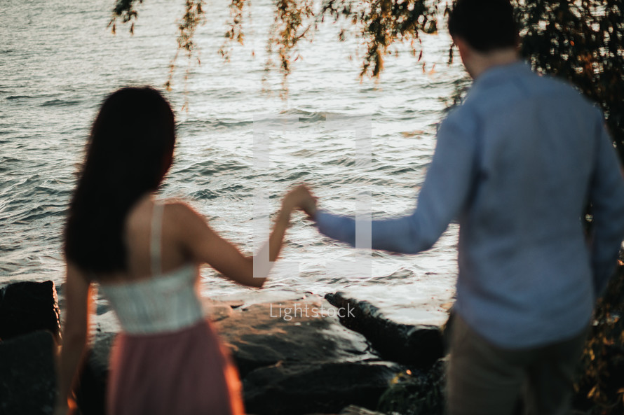 a couple holding hands on a rocky shore 