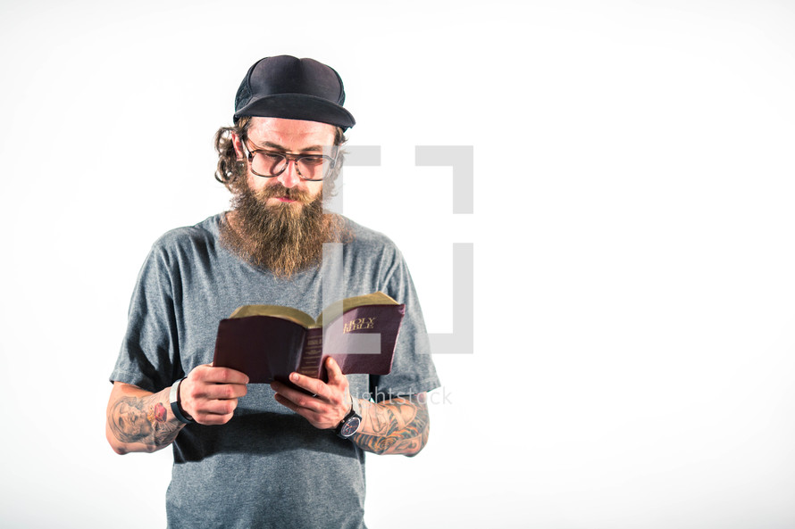 man with tattoos reading a Bible 
