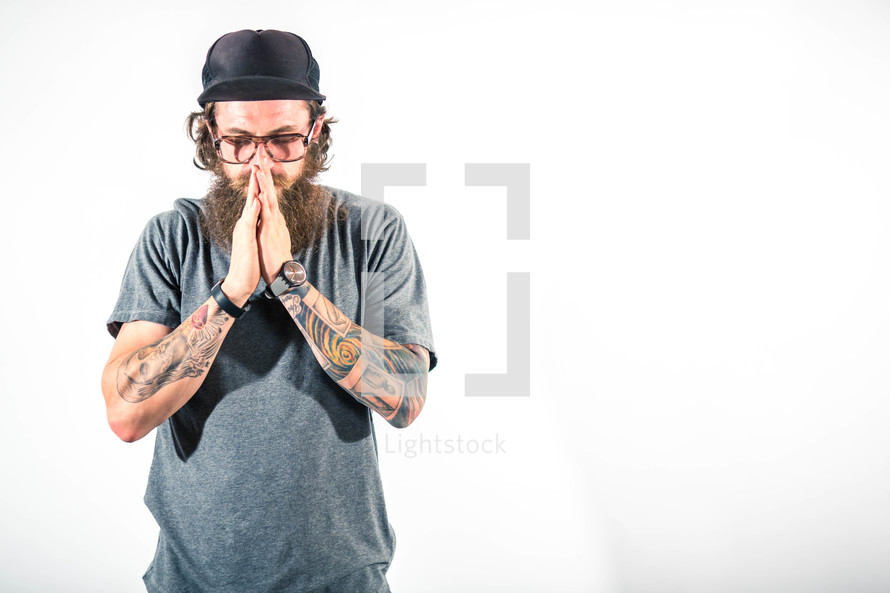 man with tattoos in prayer 