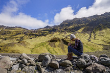a woman sitting on a rock praying outdoors in Iceland 