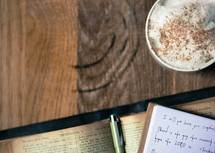 notes in a journal on an open Bible and latte 