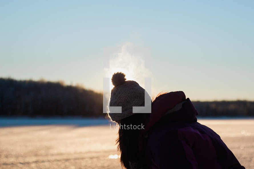 Woman in a hat in the snow at sunset