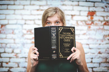 a woman hiding behind a book 