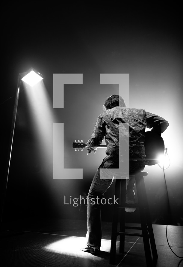 man under a spot light playing a guitar