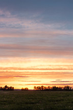 orange sky over a rural field at sunset 