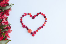 Red heart of buttons with border of red flowers on a white background