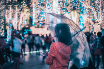 a woman walking outdoors at night carrying an umbrella in a city 