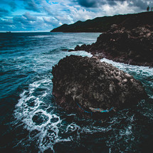 waves crashing into a small rocky island 