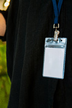 Woman in a black shirt wearing a lanyard while holding a door open.