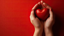 Female hands holding a red heart on a red background with copy space