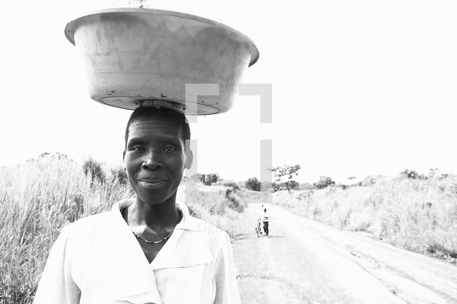 woman walking with a bucket on her head