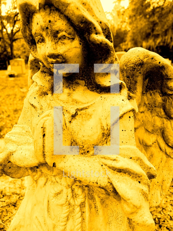 Yellow praying angel in a graveyard