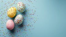 Easter eggs on blue background with sprinkles. Pink, yellow and blue pastel colors. Easter concept. Copy space.