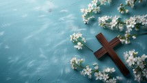 Wooden cross and white flowers on blue background. Easter concept.