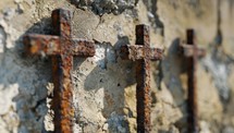 Three Rusty Metal Crosses on Weathered Concrete Wall