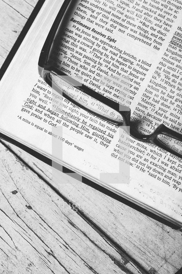 Reading glasses on top of pages of Bible open to Luke 18.