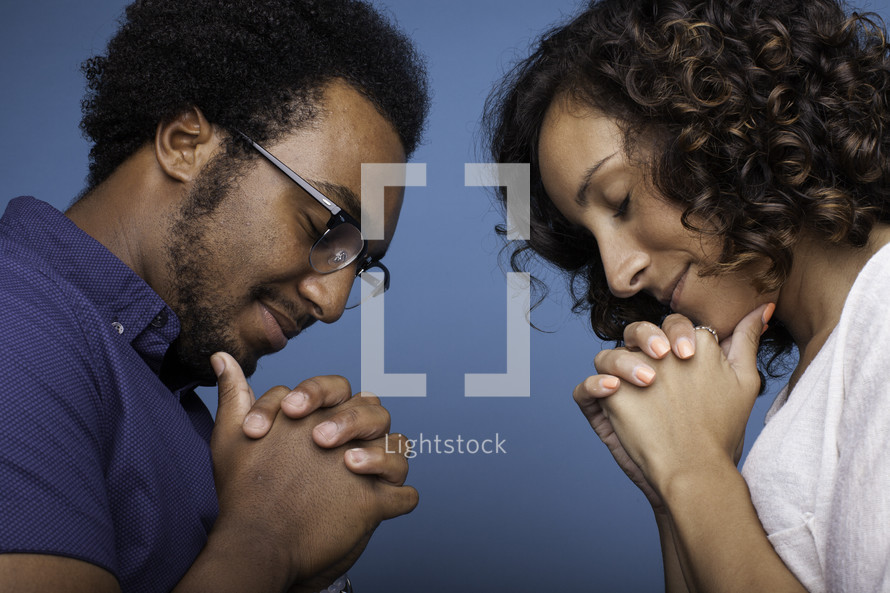 a couple with bowed heads praying together 