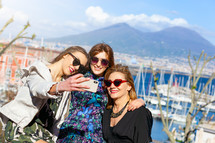 Three tourists take a selfie in front of the volcano of Naples called Vesuvio.