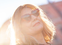 Close up portrait of a woman with red sunglasses and blonde hair.