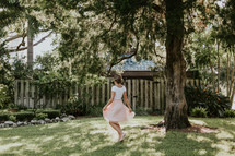 a graceful woman in a dress walking through a backyard 