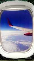 wing of an airplane from the view of an airplane window passenger seat in a commercial aircraft,