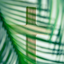 Wooden cross through the leaves of a palm branch