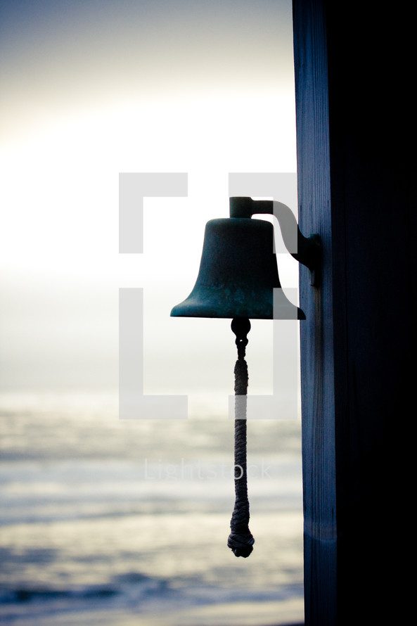 a bell and the ocean in the background