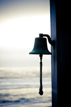 a bell and the ocean in the background