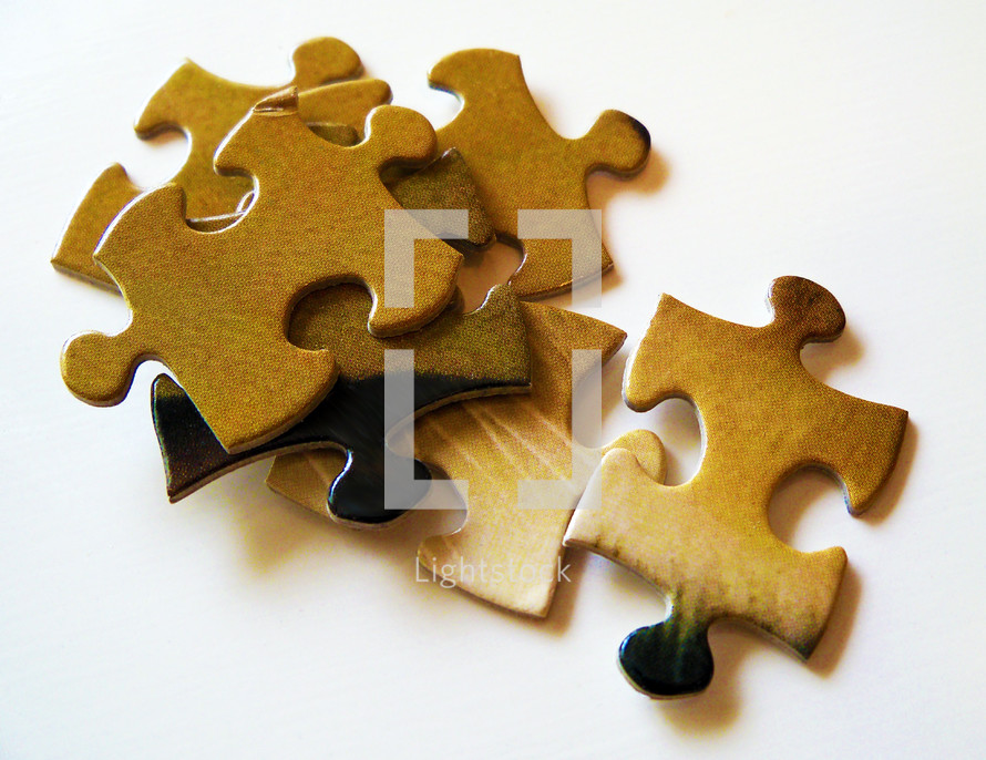 Several pieces of a jigsaw puzzle with various brown, black and beige colors lying on a white background. How many times do we feel that our life is like the pieces of a puzzle that are intricate and difficult to piece together when all we have to do is trust the Lord knowing that He has a plan for our life and He knows how to fit the puzzle of our life together.