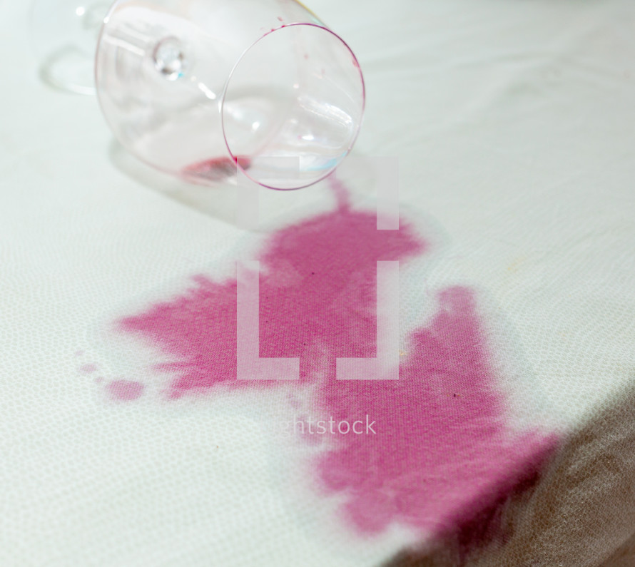 Spilled wineglass with a red spot on tablecloth