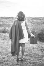 graduate in a dress holding her cap and gown 