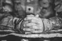 military man with praying hands over an American flag 