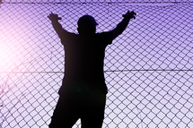 man grabbing a metallic fence feeling freedom