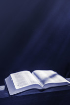 Open bible in beams of light with dust particles