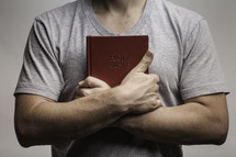 man holding a Bible over his heart 