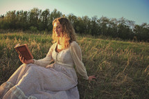a young adult reading devotional book in a meadow