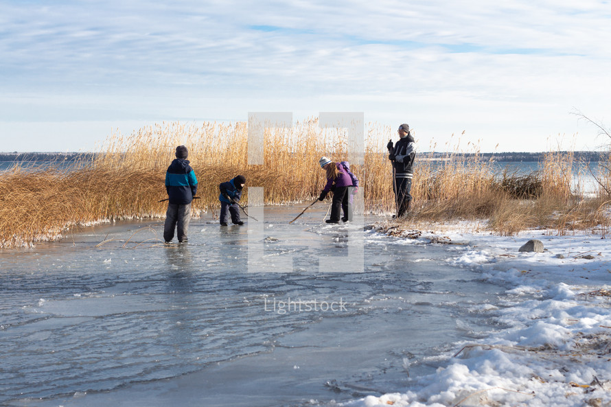 kids playing hockey with sticks on a family pond 