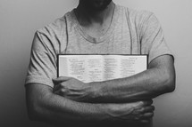 man holding an opened Bible against his chest 