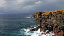 Dramatic clouds in the background of the coastal sea cliffs of Kona, Hawaii.