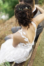 bride and groom sitting on a bench outdoors 