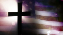 Cross in front of waving US flag.