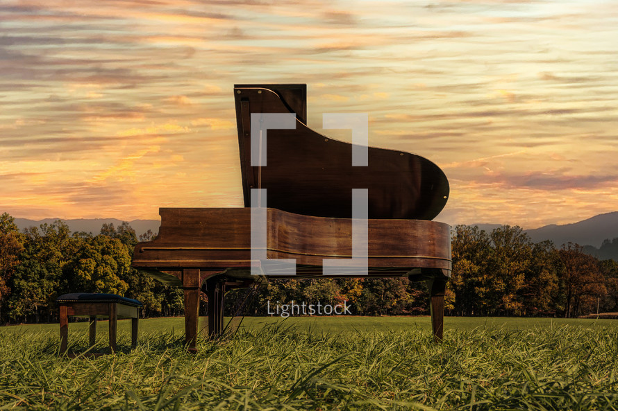 grand piano in a field at sunset 
