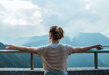 woman looking at mountains over a railing 