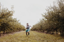 boy running in an orchard 