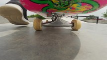 Riding a pink skateboard at a skate park.