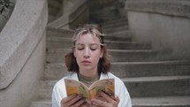 Young Woman reading a book on the stairs