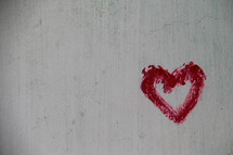 Red painted heart on textured wall background