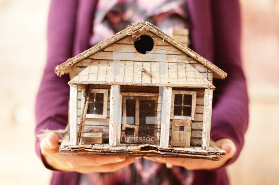Woman holding a homemade bird house.