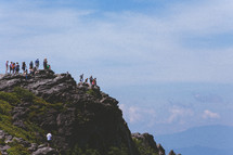 people standing at the top of a rock peak 
