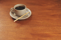 A white cup of coffee on a brown table.